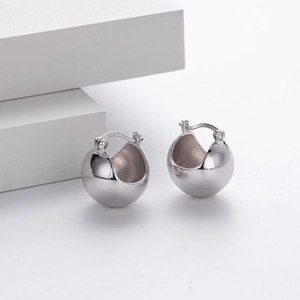 Detailed close-up of polished S925 sterling silver ball earrings on a stone base