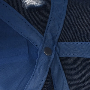 Macro detail of inner seams and metal rivet on distressed blue denim baseball cap