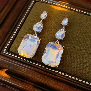 Macro shot of holographic gemstone earrings with teardrop and rectangle cuts on velvet tray