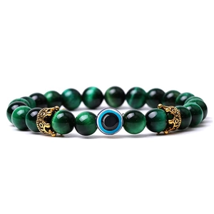 Detailed view of green tiger eye beads with evil eye and gold crown charms bracelet