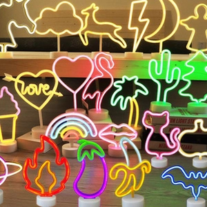 Various LED neon sign shapes like flamingo and cactus on wooden stairs with vibrant glow