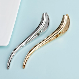 Detail of minimalist S-shaped metal hair clips in polished gold and silver finishes