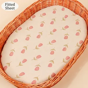 Detail of baby cradle fitted sheet with pink tulip pattern on breathable cotton gauze fabric