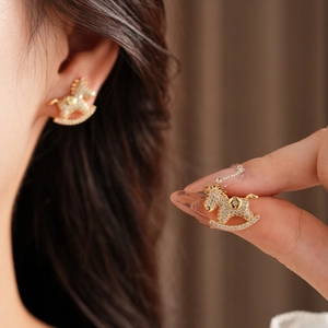 Detailed close-up of gold rocking horse earrings with sparkling crystal pavé setting