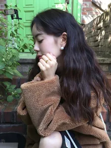 French vintage pearl earrings and gold ring styled with a brown teddy jacket in a street shot