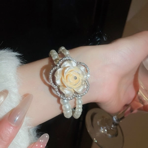 Close-up of a double-layered pearl bracelet with a rhinestone-edged resin rose pendant