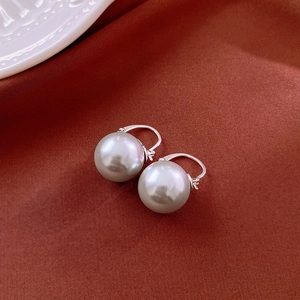 Gros plan détaillé de boucles d'oreilles perles blanches sur un tissu de soie rouge foncé