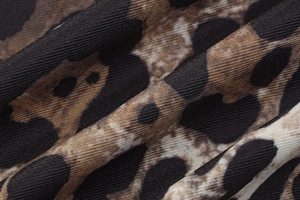 Vista macro del tessuto leopardato con trama saia fine e motivo animalier marrone scuro
