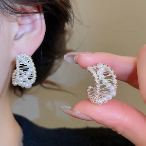 Detail of 18k gold plated C-shaped earrings with intricate wire-wrapped pearls