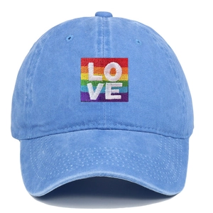 Detailed view of rainbow pride flag patch with white LOVE embroidery on blue washed denim cap