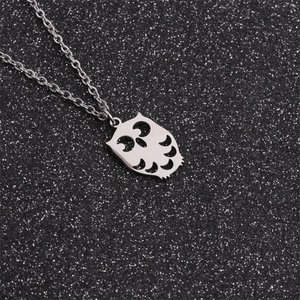 Macro shot of polished stainless steel owl pendant on a silver chain with dark background