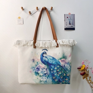 Detailed view of a bohemian style tote bag with fringe and colorful peacock print