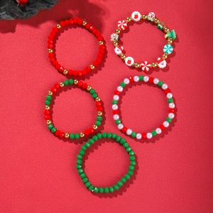 Detail view of five Christmas beaded bracelets with Santa and tree charms on red background
