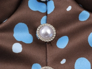 Macro view of round pearl buttons with metal lace trim on vintage polka dot satin fabric