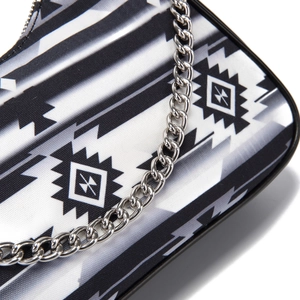 Detail of bohemian geometric pattern fabric and silver metal chain on the handbag