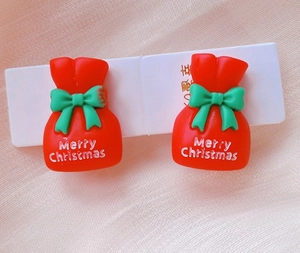 Detail view of festive red gift bag clip-on earrings with green bows for Christmas