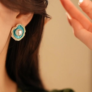 Détail de boucles d'oreilles feuille émail bleu avec perle et bord en cristaux