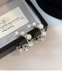 Detailed view of silver C-shaped pearl earrings with inlaid rhinestones and French design