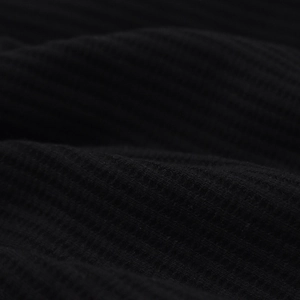 Detailed macro view of black waffle weave knit fabric texture with soft folded layers