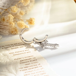 Silver cross pendant hoop earring with micro-set zircons on vintage paper background