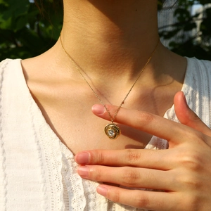Detail of 18K gold-plated twisted chain necklace with a crystal-centered rose pendant