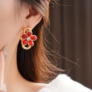 Close-up of golden vintage flower earring with red petals and sparkling crystal center