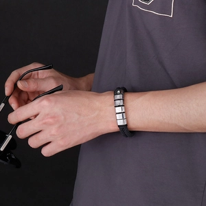 Macro view of men's layered leather bracelet with engraved stainless steel beads