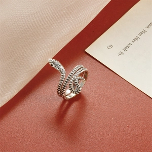 Macro detail of a silver snake ring with scales on vintage paper and silk fabric
