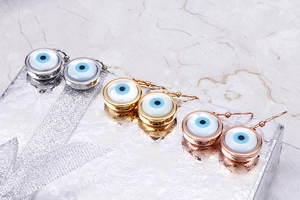 Detail of evil eye drop earrings in gold, silver and rose gold finishes on a gift box