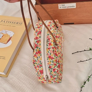 Close-up of floral storage bag with zipper closure and brown leather handles