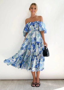 Detail of off-shoulder tiered dress featuring puff sleeves and blue abstract polka dots