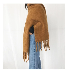 Close-up of thick brown knit scarf with fringe tassels shown on a model
