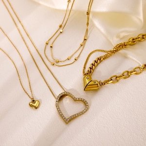 Elegant gold heart pendant necklaces with crystals on white silk background