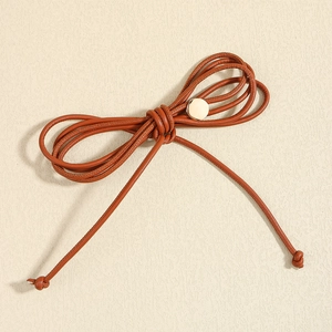 Dettaglio di una corda in vita in pelle PU marrone annodata con bottone dorato