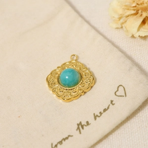 Close-up of vintage gold pendant with turquoise stone on a linen pouch with flowers