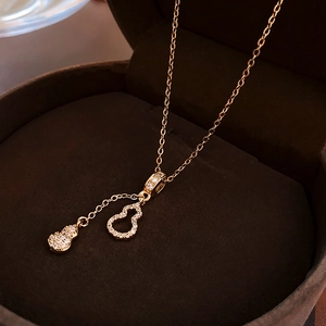 Détail du collier pendentif gourde dorée avec zircons dans son écrin à bijoux luxueux