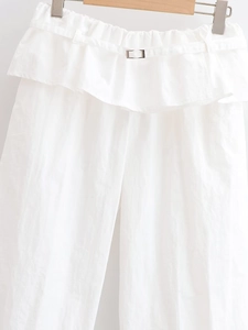 Détail du pantalon blanc taille haute avec taille volantée et boucle métallique