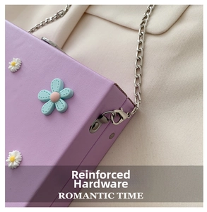 Detail of reinforced silver chain hardware on a purple crossbody bag with daisy decor