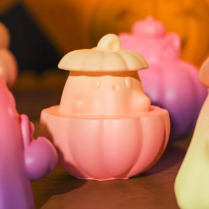 Close-up of a cute white ghost figurine inside a pink pumpkin base with warm lighting