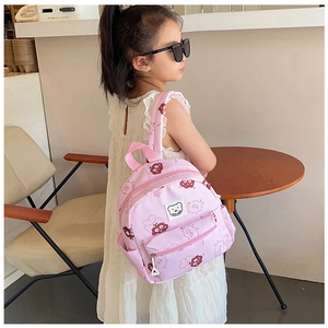 Bambina che indossa uno zainetto rosa con orsetto in un ambiente interno accogliente