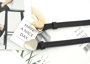 Close-up of heart-shaped gold and silver metal buckles on black slim leather belts