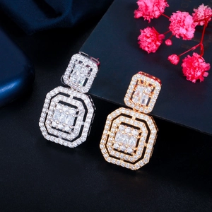 Macro shot of geometric earrings in gold and silver set with sparkling zircons