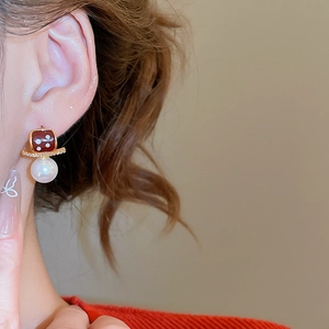 Detail of red enamel pearl earrings with gold plating and zircons worn by model
