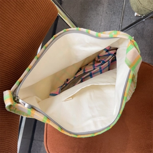 Interior view of plaid canvas tote bag showing inner pocket and metal zipper closure