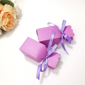 Close-up of purple candy-shaped gift boxes with matching silk ribbon bows on white background