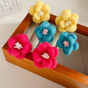 Vue détaillée de boucles d'oreilles fleurs en feutre colorées en jaune, bleu et rose