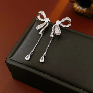 Close-up of bowknot tassel earrings with silver finish and sparkling zircon stones