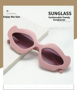 Macro view of pink mouth-shaped punk sunglasses with polarized lenses on white marble