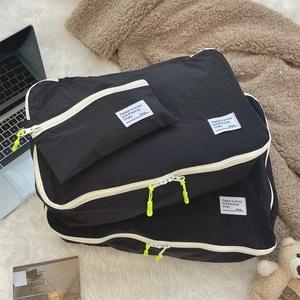 Three-piece set of black waterproof travel organizers with yellow zipper pulls on plush rug