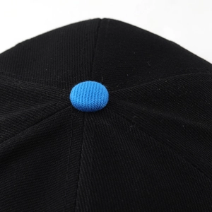 Macro shot of black twill baseball cap crown with a contrasting blue fabric top button